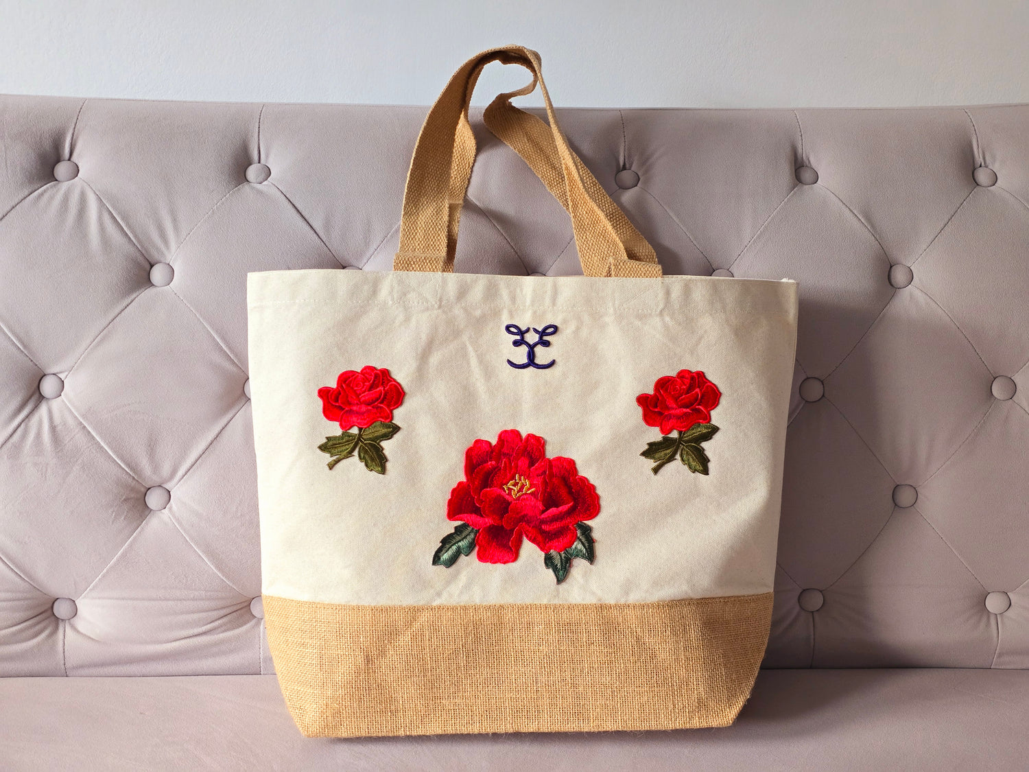 Belle Elodie sustainable and eco-friendly embroidered designer canvas tote bag made with natural cotton and jute with red flowers embroideries front on a sofa